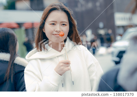 一位二十多歲的女性在旅遊區享用街頭小吃的場景。 一位二十多歲的女性在旅遊區享用街頭小吃的場景。 138017370