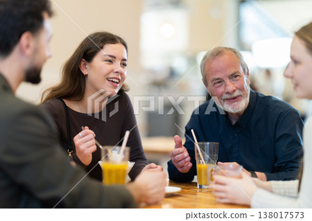 Friendly family talking over dinner in modern cafe Friendly family talking over dinner in modern cafe 138017573