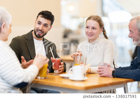 Friendly family talking over dinner in modern cafe Friendly family talking over dinner in modern cafe 138017591