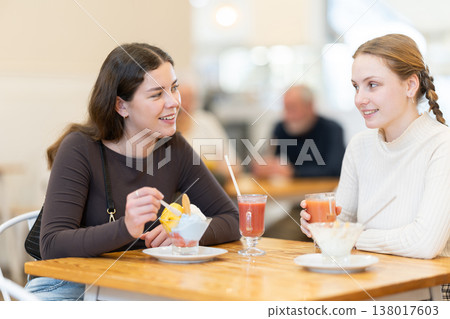 Young woman with teen girl chatting and gossip while drink latte coffee, eating ice cream Young woman with teen girl chatting and gossip while drink latte coffee, eating ice cream 138017603