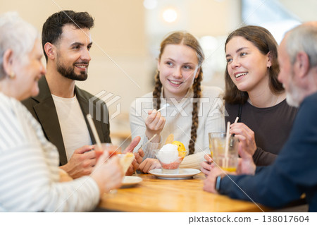 Friendly family talking over dinner in modern cafe Friendly family talking over dinner in modern cafe 138017604