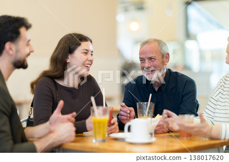 Friendly family talking over dinner in modern cafe Friendly family talking over dinner in modern cafe 138017620