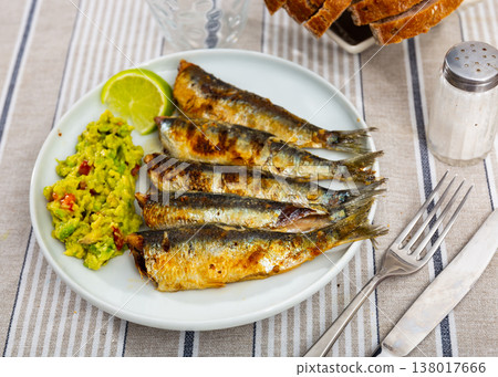 Delicious grilled sardines with guacamole and lemon closeup 138017666