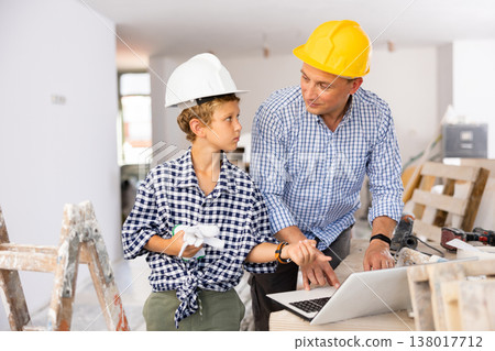 Man architect and boy using laptop while discussing working process in house being renovated 138017712