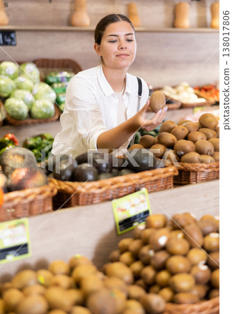 Interested young girl choosing ripe soft kiwis in store Interested young girl choosing ripe soft kiwis in store 138017806