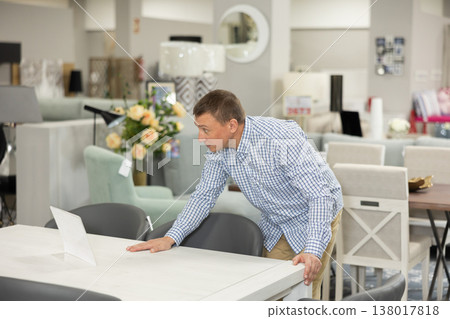 Adult man choosing functional dining table in furniture shop 138017818