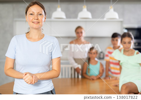 Portrait of happy mother of large family against the background of children and his wife in the interior of house Portrait of happy mother of large family against the background of children and his wife in the interior of house 138017822