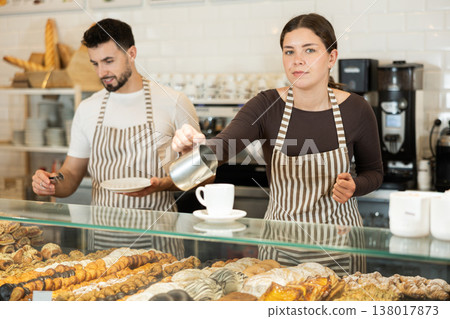 Girl cafe worker pours coffee from cezve coffee pot into cup Girl cafe worker pours coffee from cezve coffee pot into cup 138017873