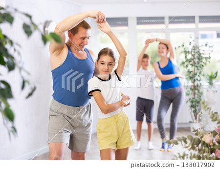 Active school girl practicing dance in pair with her sporty middle-aged father in dance hall during family training 138017902