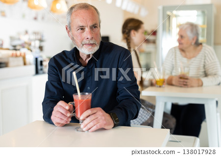 Elderly man drinking tomato juice in coffee shop Elderly man drinking tomato juice in coffee shop 138017928