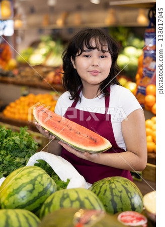 Positive girl seller of grocery supermarket with ripe watermelon in her hands 138017945