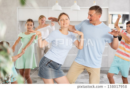 Happy cheerful parents together with children dancing in living room at home Happy cheerful parents together with children dancing in living room at home 138017958