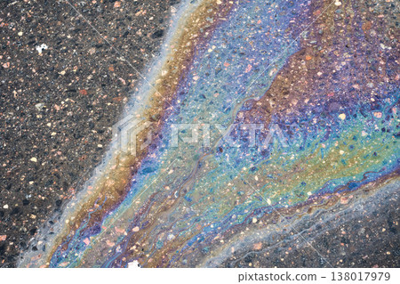 Oil puddle on tarmac showing unique multicolored patterns. Fuel leakage impacts the environment, forming a vibrant texture Oil puddle on tarmac showing unique multicolored patterns. Fuel leakage impacts the environment, forming a vibrant texture 138017979