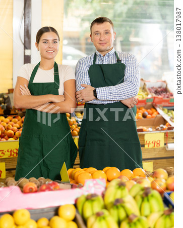 Smiling father and daughter, owners of green grocery store, standing among stalls of fruits and vegetables Smiling father and daughter, owners of green grocery store, standing among stalls of fruits and vegetables 138017987