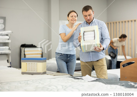 Married couple chooses and discusses mattress filling in furniture store Married couple chooses and discusses mattress filling in furniture store 138018004