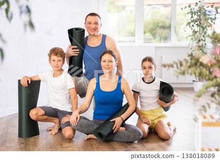 Portrait of happy family of four with mats in their hands after doing yoga in gym 138018089
