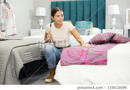 Young girl choosing fabric foot throw for bedroom in furnishing store 138018096