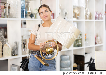 Young woman is seen shopping for table lamp with lampshade in stylish home decor store 138018103