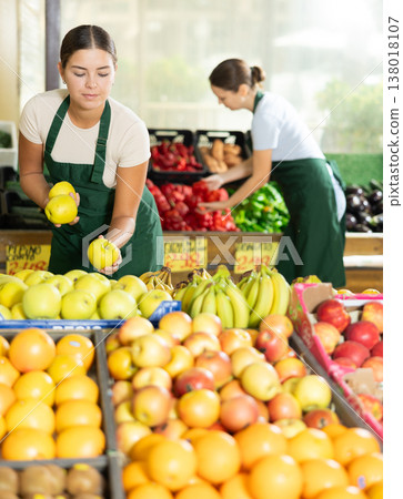 Smiling girl seller is showing assortment of apples in vegetable shop Smiling girl seller is showing assortment of apples in vegetable shop 138018107