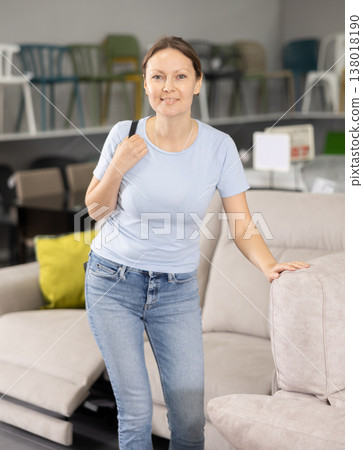 Positive woman chooses modern sofa in furniture store Positive woman chooses modern sofa in furniture store 138018190