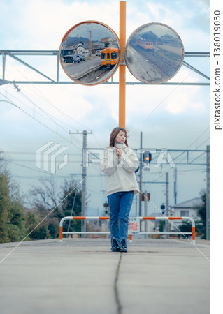A tourist portrait of a woman in her 20s standing in front of a local train station. A tourist portrait of a woman in her 20s standing in front of a local train station. 138019030