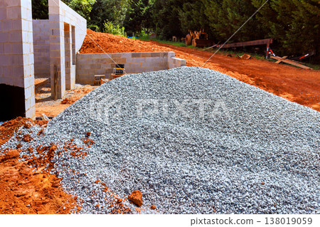 Construction workers have piled gravel near building site with foundations laid 138019059
