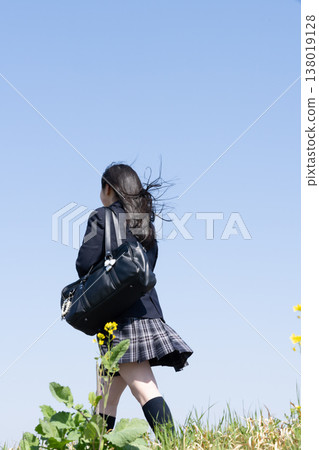 An emotional scene of youth commuting to school. A student in their uniform, carrying a school bag, takes a step forward (face not shown). 138019128