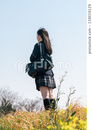 An emotional scene of youth commuting to school. A student in their uniform, carrying a school bag, takes a step forward (face not shown). An emotional scene of youth commuting to school. A student in their uniform, carrying a school bag, takes a step forward (face not shown). 138019129