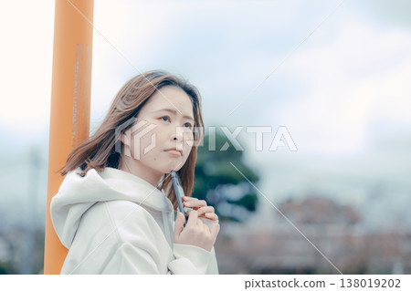 一位二十多歲的女性在旅遊景點看著她的智慧型手機的側面肖像。 138019202