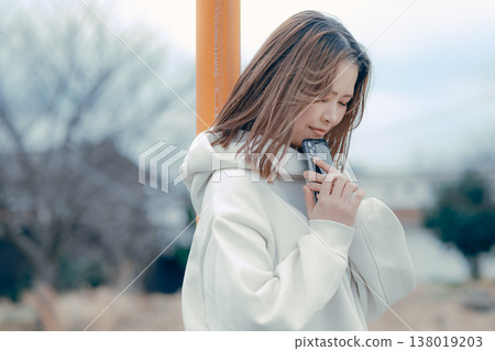 A profile portrait of a woman in her 20s looking at her smartphone in a tourist spot. A profile portrait of a woman in her 20s looking at her smartphone in a tourist spot. 138019203