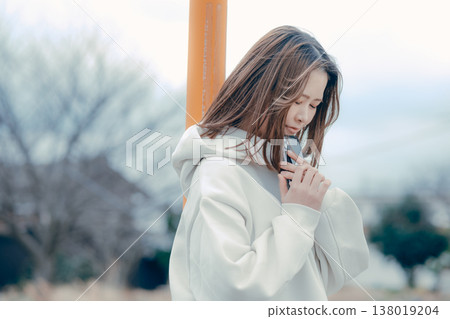 A profile portrait of a woman in her 20s looking at her smartphone in a tourist spot. A profile portrait of a woman in her 20s looking at her smartphone in a tourist spot. 138019204