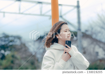 一位二十多歲的女性在旅遊景點看著她的智慧型手機的側面肖像。 138019205