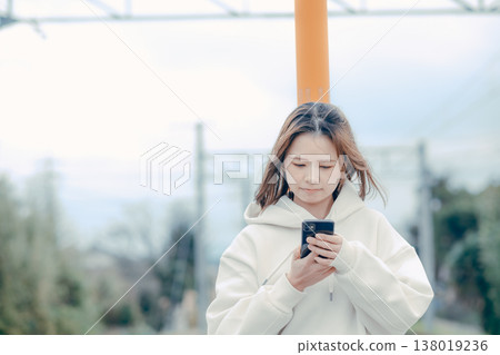 一位二十多歲的女性在旅遊景點查看智慧型手機的正面肖像。 138019236