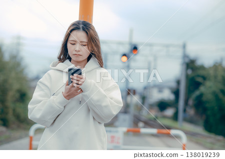 一位二十多歲的女性在旅遊景點查看智慧型手機的正面肖像。 138019239