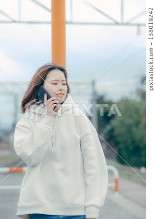 A frontal portrait of a woman in her 20s checking her smartphone at a tourist spot. A frontal portrait of a woman in her 20s checking her smartphone at a tourist spot. 138019242