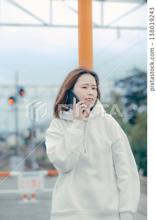 一位二十多歲的女性在旅遊景點查看智慧型手機的正面肖像。 138019243