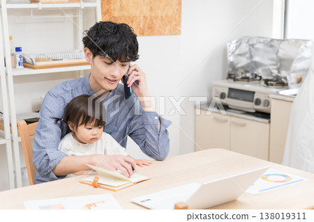 一位年輕的父親一邊在餐廳打電話一邊照顧孩子：在家工作時照顧孩子的場景。 138019311