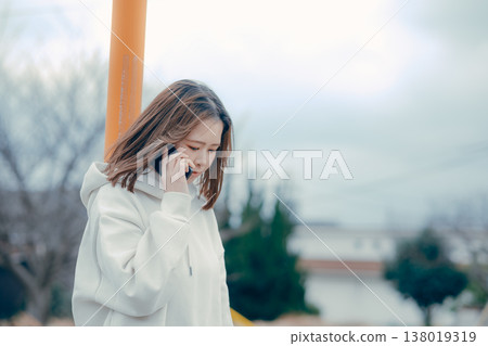 A profile portrait of a woman in her 20s talking on the phone outdoors. A profile portrait of a woman in her 20s talking on the phone outdoors. 138019319