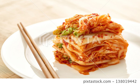 Close-up of Korean cabbage kimchi on a white plate with wooden chopsticks. 138019442