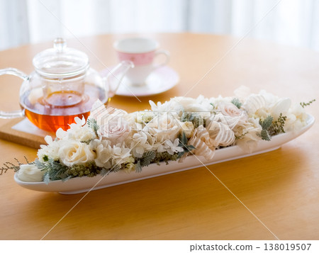 優雅的下午茶時光，桌上擺放著一束白玫瑰花和一杯茶。 138019507