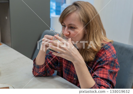 Women calmly enjoy drinks in different kitchen settings. A young mother drinks morning coffee at the kitchen table. A woman drinks cocoa early in the morning 138019632
