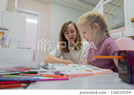 mother and daughter doing homework at kitchen table, warm focused atmosphere, colorful school supplies scattered, mother guiding child through workbook, concentration and supportive bond, soft natural mother and daughter doing homework at kitchen table, warm focused atmosphere, colorful school supplies scattered, mother guiding child through workbook, concentration and supportive bond, soft natural 138019704