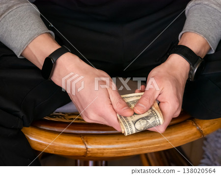 Man holding United States dollar banknote in hand. Currency exchange and financial savings concept. Investor counting cash income for budget management. Economic wealth and prosperity. 138020564