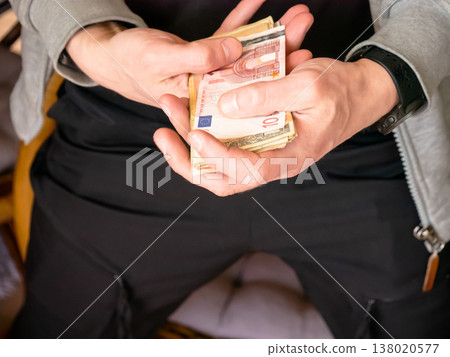 Man holding stack of Euro banknotes in hand. Counting paper money for financial transaction. Wealth, savings and investment concept. Economic growth and commercial banking operations. 138020577