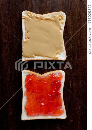 從正上方俯視的桌子背景，可以看到塗了花生醬和草莓醬的麵包片。 138020891