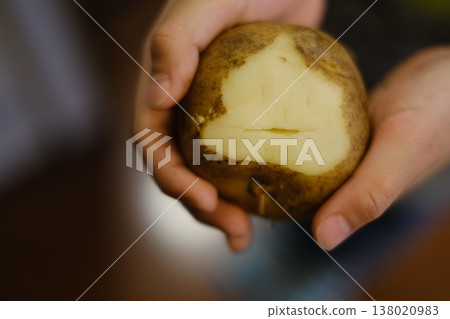一個削成便便形狀的馬鈴薯和一隻孩子的手 138020983