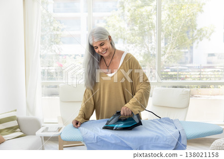 Smiling woman smoothing-out husband shirt with iron Smiling woman smoothing-out husband shirt with iron 138021158