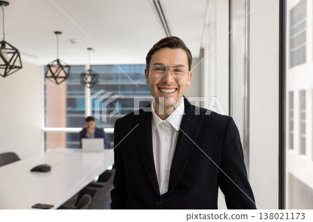 Confident businessman in black suit standing in contemporary meeting room Confident businessman in black suit standing in contemporary meeting room 138021173