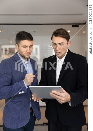 Two businessmen analyze or discuss important data on digital tablet Two businessmen analyze or discuss important data on digital tablet 138021181