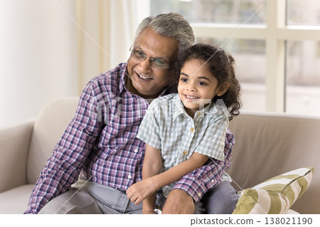 Little 6s great-grandson and older 70s great-grandfather sitting on sofa Little 6s great-grandson and older 70s great-grandfather sitting on sofa 138021190